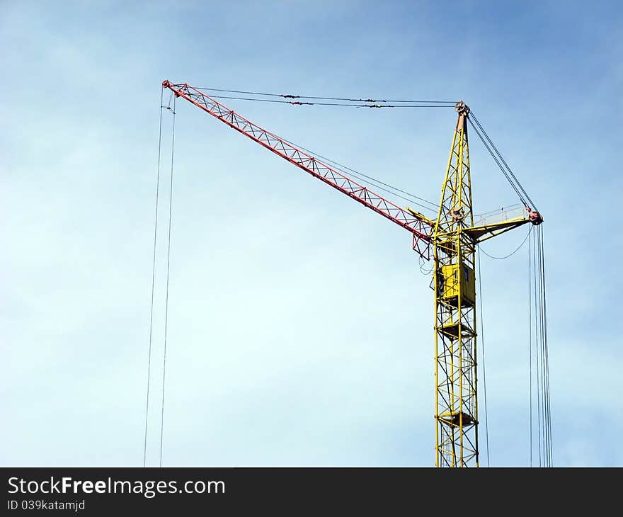 Silhouette of lifting crane against a background of blue sky