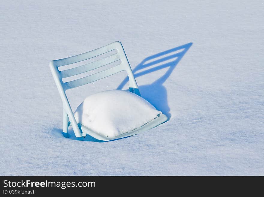 A plastic chair stuck in the snow. A plastic chair stuck in the snow