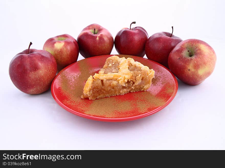 Apple Pie - a slice on a plate decorated with cinnamon and some red apples