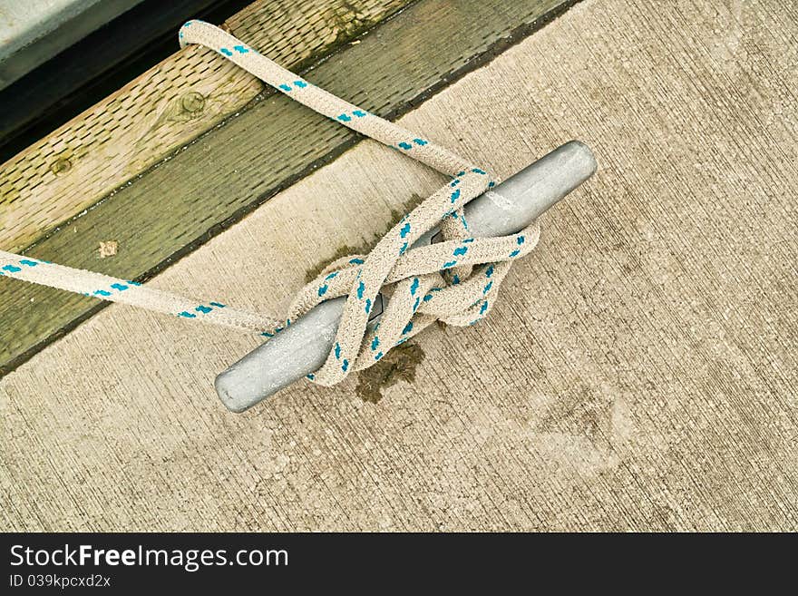 Rope tied in cleat hitch on marina dock.