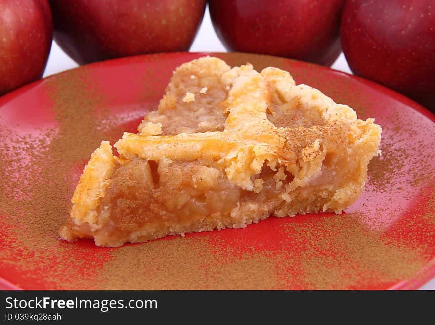 Apple Pie - a slice on a plate decorated with cinnamon and some red apples