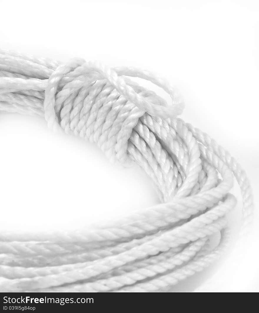 White rope is coiled on white background; closeup of wrapped coil. White rope is coiled on white background; closeup of wrapped coil