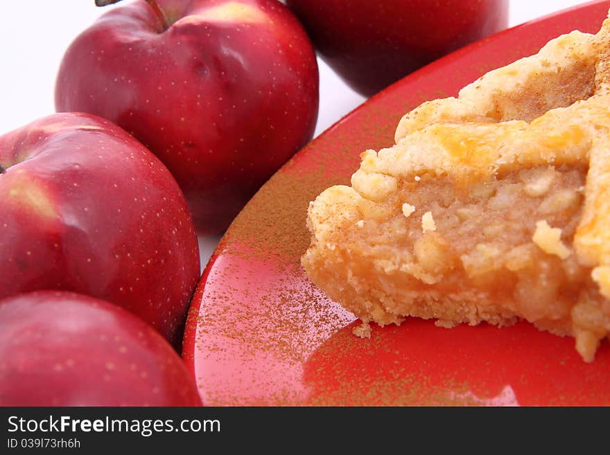 Apple Pie - a slice on a plate decorated with cinnamon and some red apples