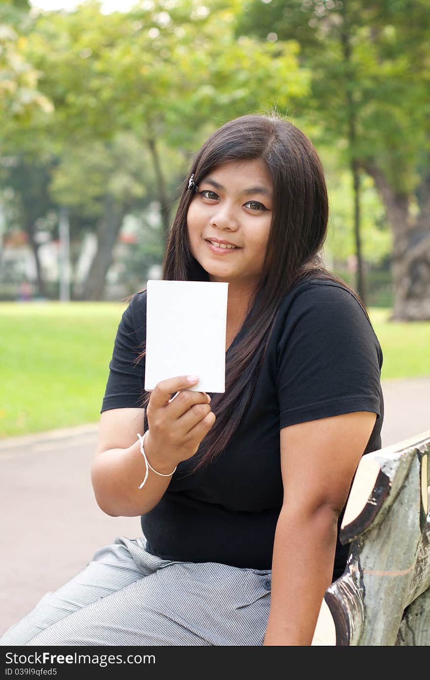 Women in the garden and holding a white card.