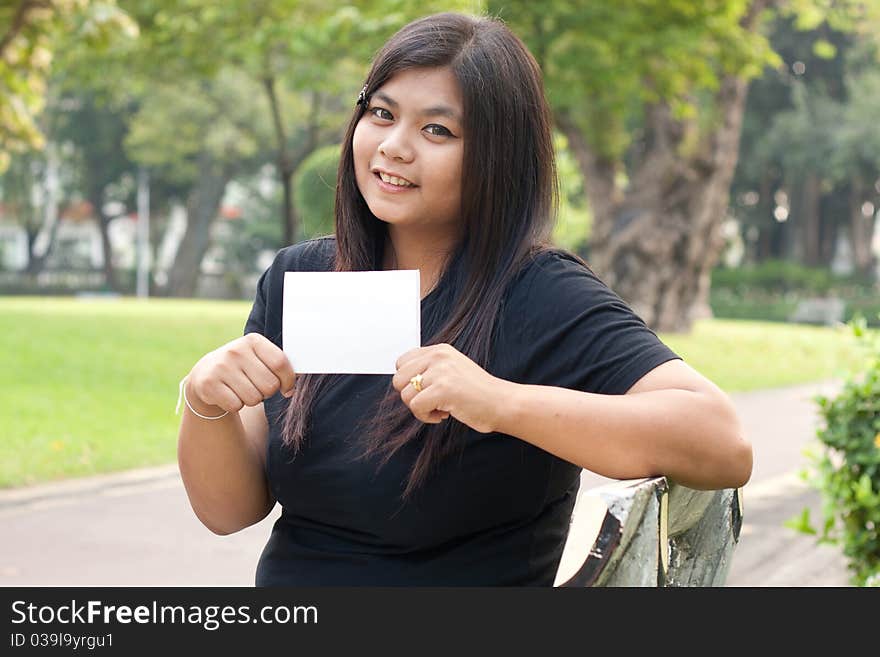 Women in the garden and holding a white card.