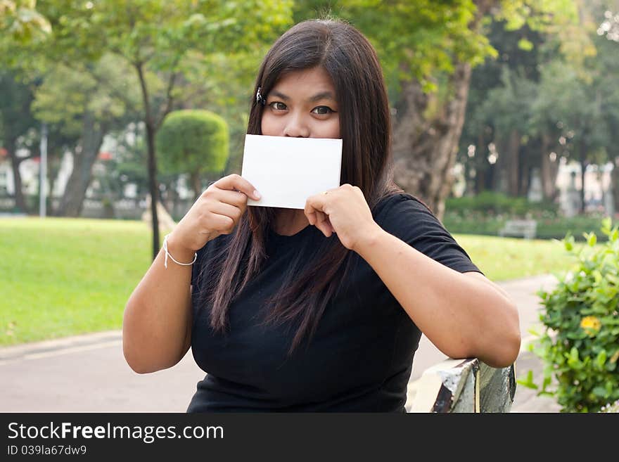 Women sitting in the park and hold a white card.