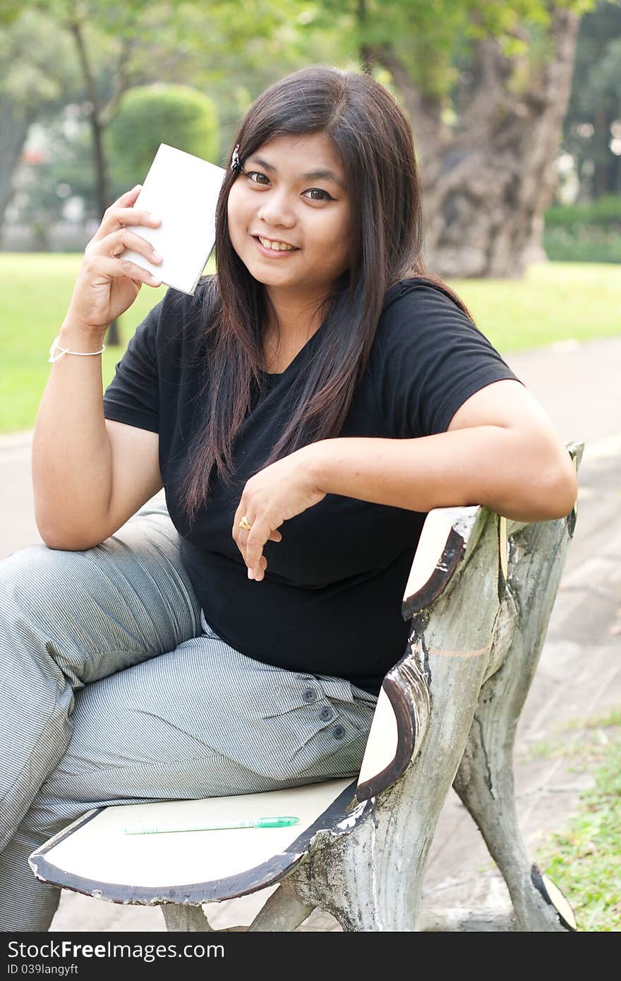 Women sitting in the park and is writing a notebook in it. Women sitting in the park and is writing a notebook in it.