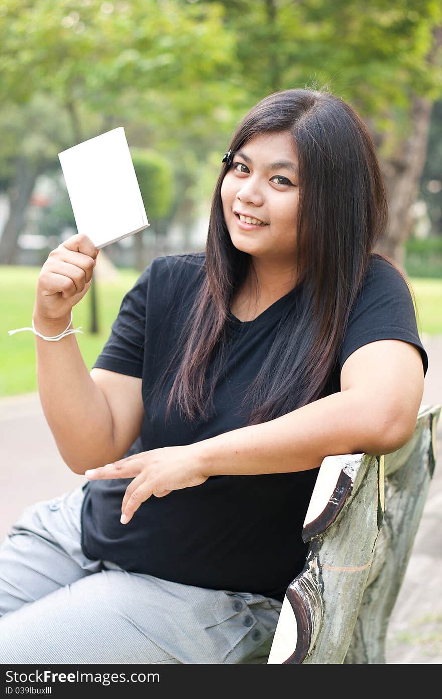 Women sitting in the park and hold a white card. Women sitting in the park and hold a white card.