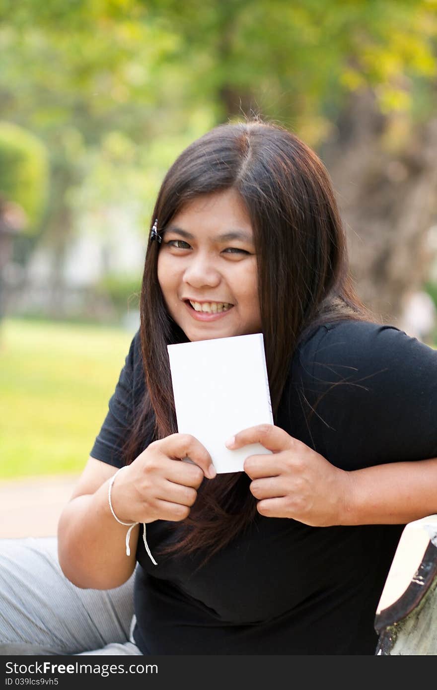 Women in the garden and holding a white card.