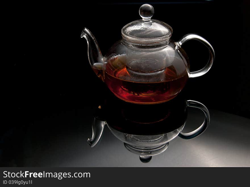 Glass teapot with the made tea on a glass surface. Glass teapot with the made tea on a glass surface