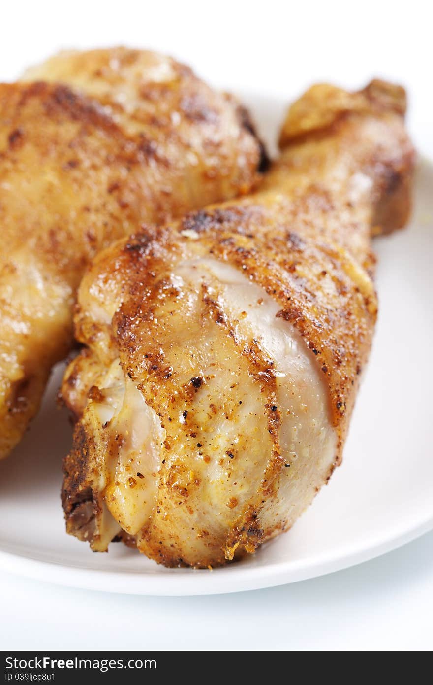 Two roasted chicken legs on plate on white background