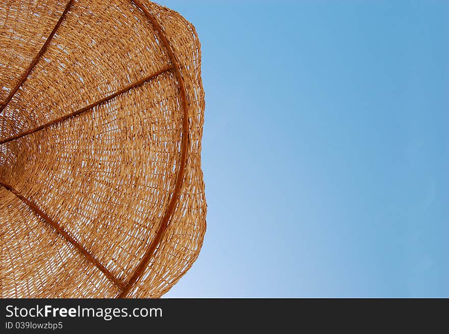 Straw sun umbrella against sunny blue sky