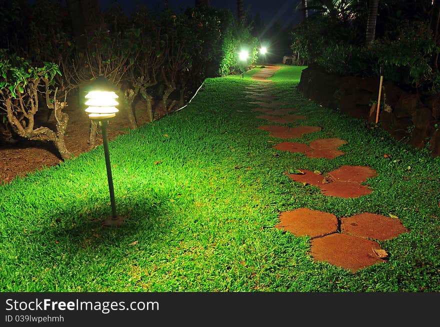 Pathway stones in a beautiful garden walkway with lamps at night. Pathway stones in a beautiful garden walkway with lamps at night