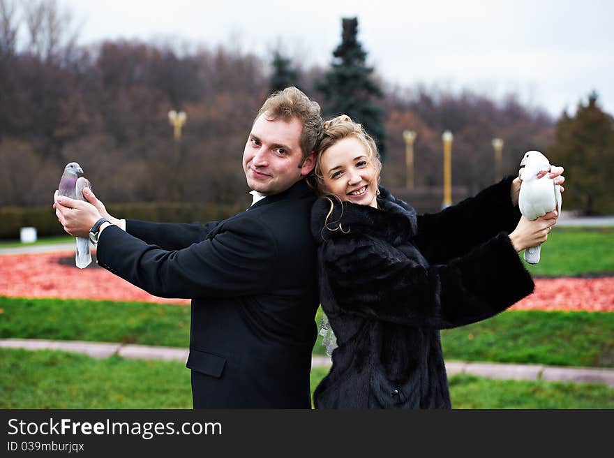 Bride and groom with pigeons on hands on wedding walk