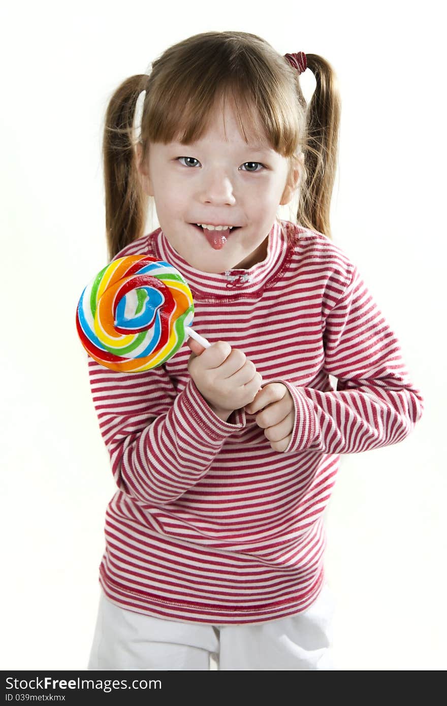 Little girl eating a lollipop atd sticking out tongue. Little girl eating a lollipop atd sticking out tongue