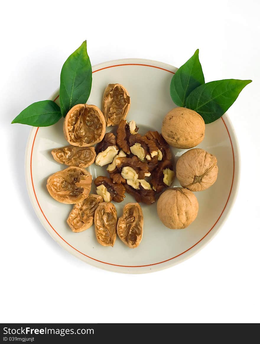 Chopped and whole walnuts on a plate. White background.