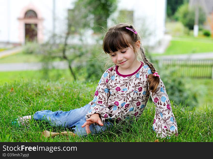 Little girl sits on grass