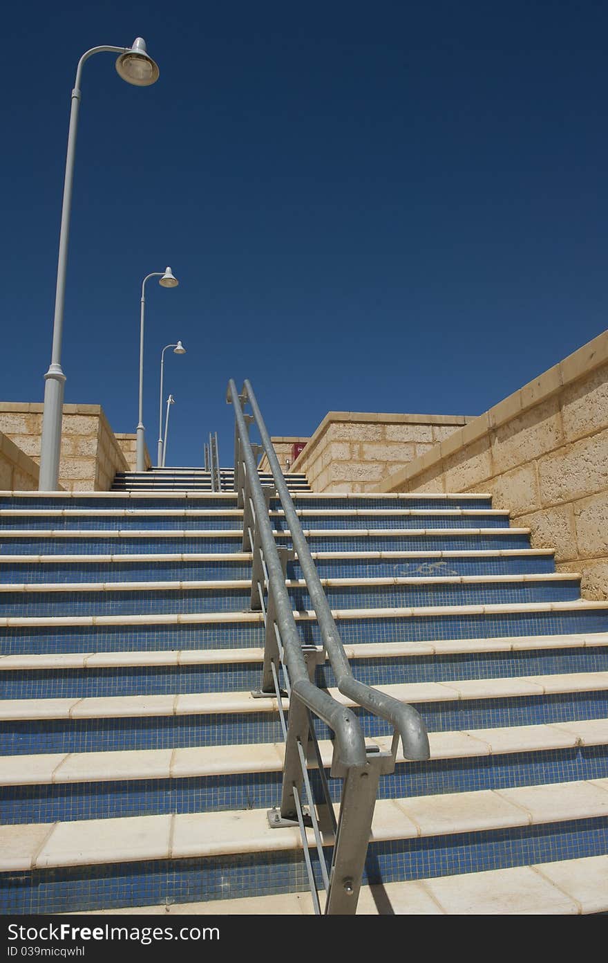 RAW-file of wide steps with with handrail and streetlights in new housing development area in Perth, Western Australia - with spotless clean blue sky as background and copy space. RAW-file of wide steps with with handrail and streetlights in new housing development area in Perth, Western Australia - with spotless clean blue sky as background and copy space.