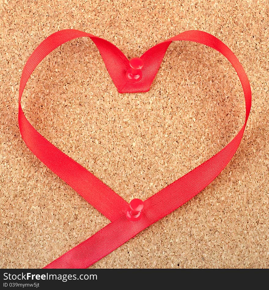 Red heart shaped ribbon pinned to cork board