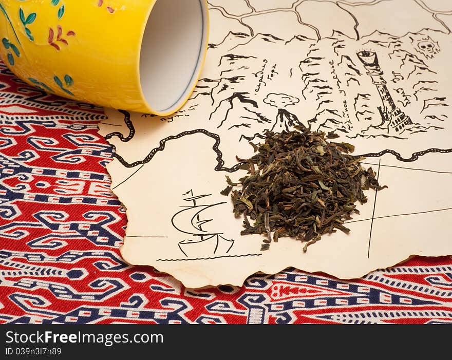 Treasure map, tea and a tea cup on an ethnic cloth