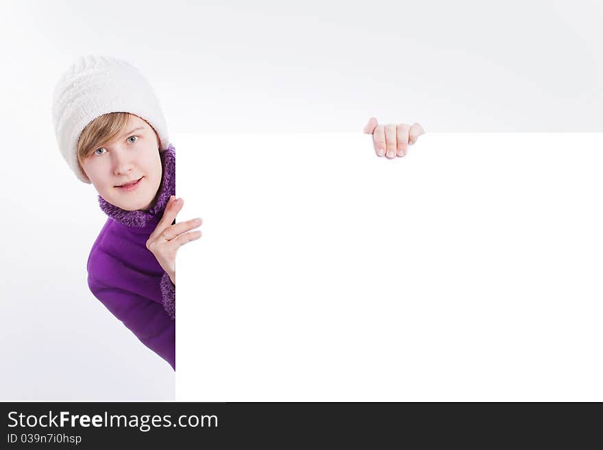 Young woman in a warm cap and a sweater showing empty white board