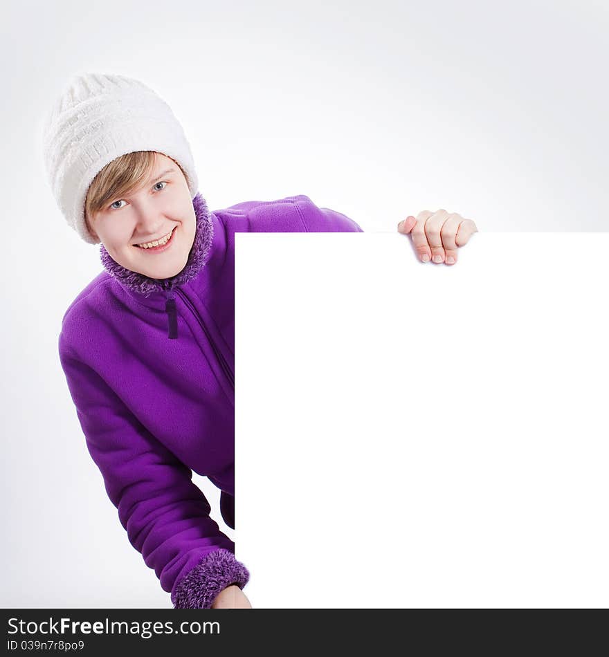 Young woman in a warm cap and a sweater showing empty white board