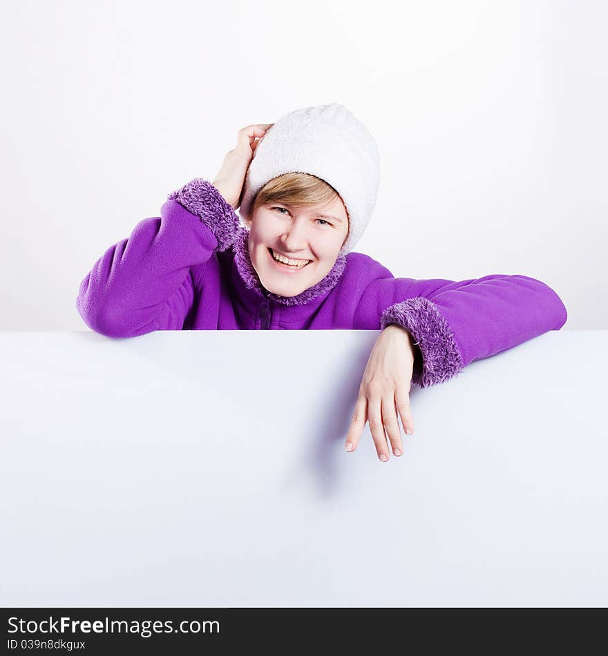 Young woman in a warm cap and a sweater showing empty white board