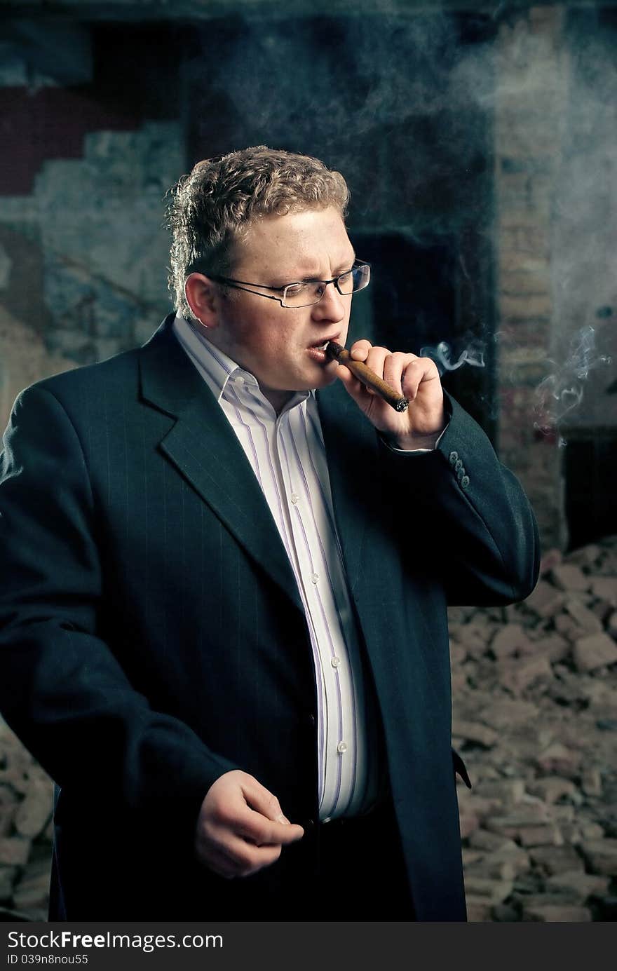 Man in black suite smoking cigar on abandoned factory background. Man in black suite smoking cigar on abandoned factory background