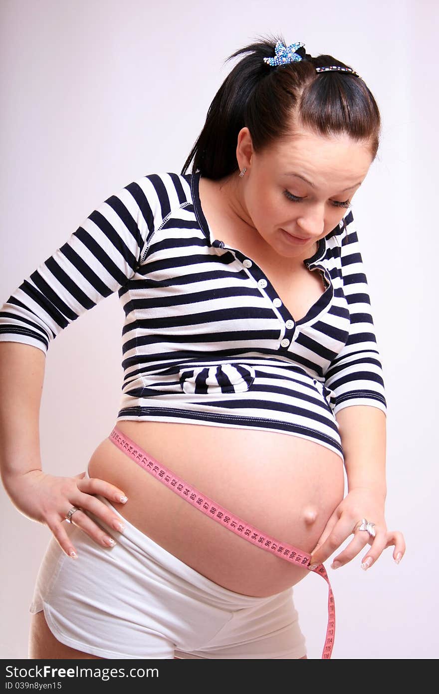 Pregnant woman measuring her belly over white