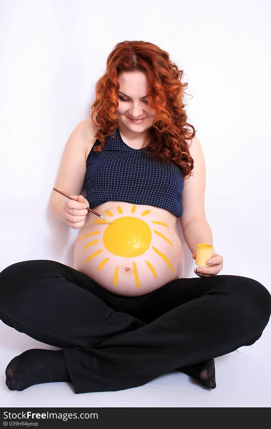 Conceptual image of happy pregnant female with painted pictures on her belly