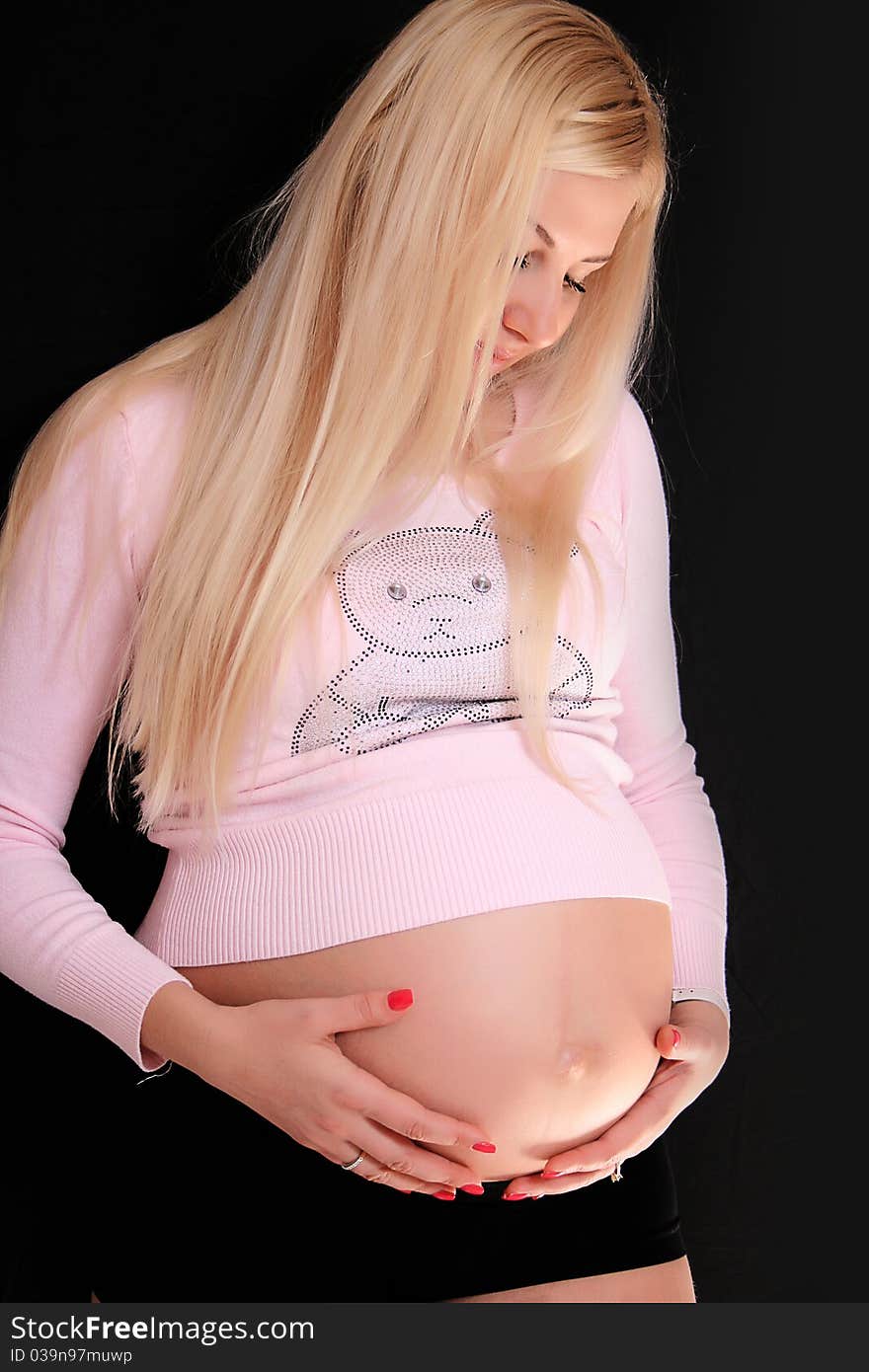 Young pregnant blond woman holding her belly