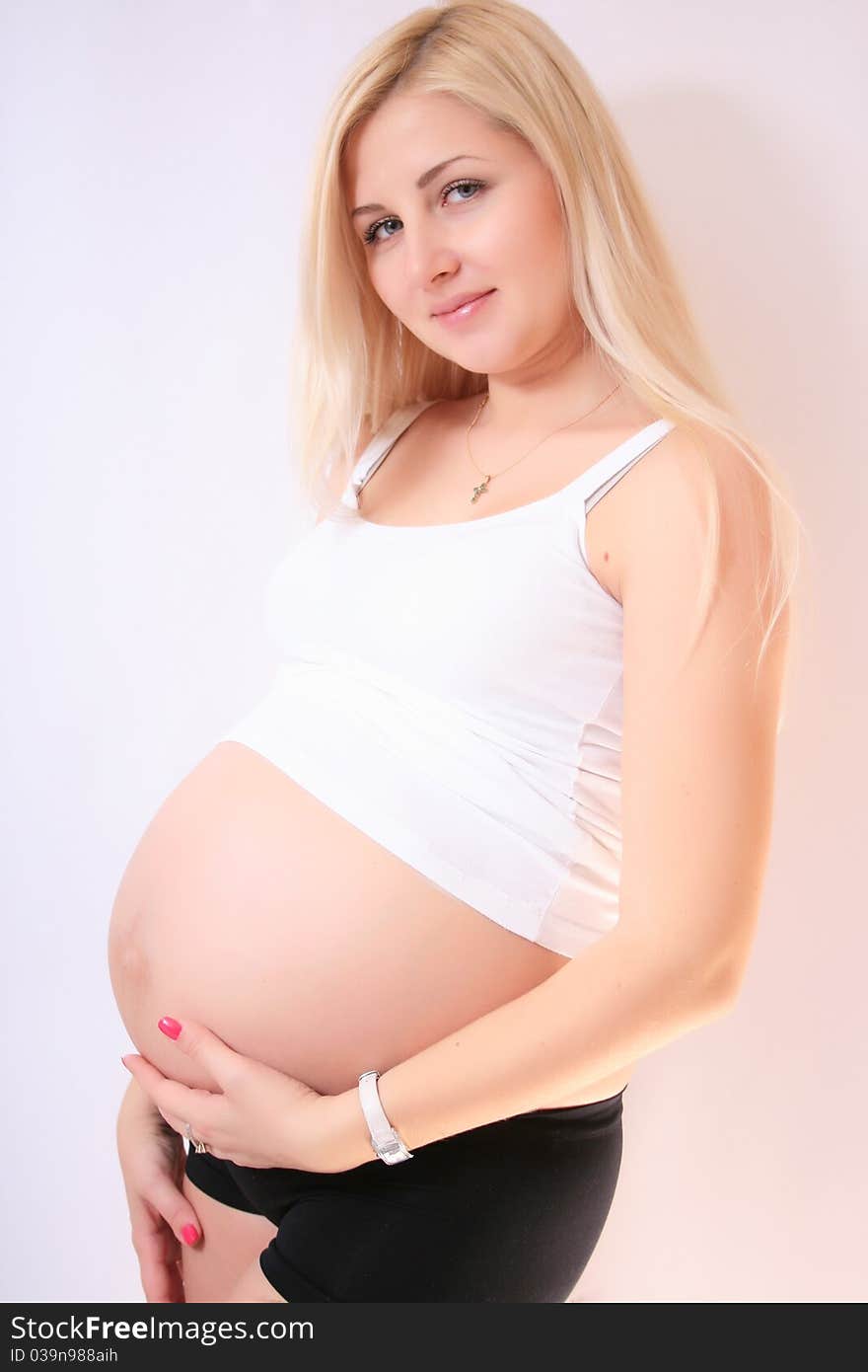 Young pregnant blond woman holding her belly