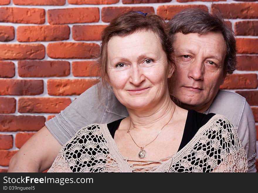 Happy seniors couple in love against brick wall