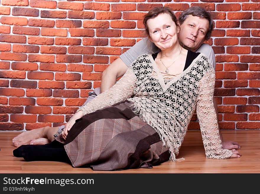 Happy seniors couple in love against brick wall