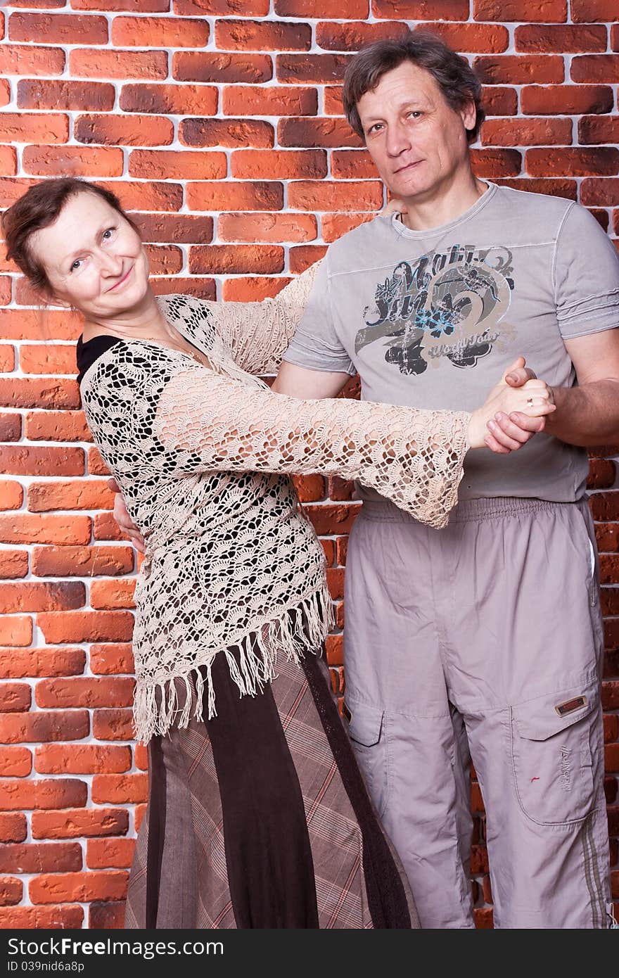 Happy seniors couple in love against brick wall