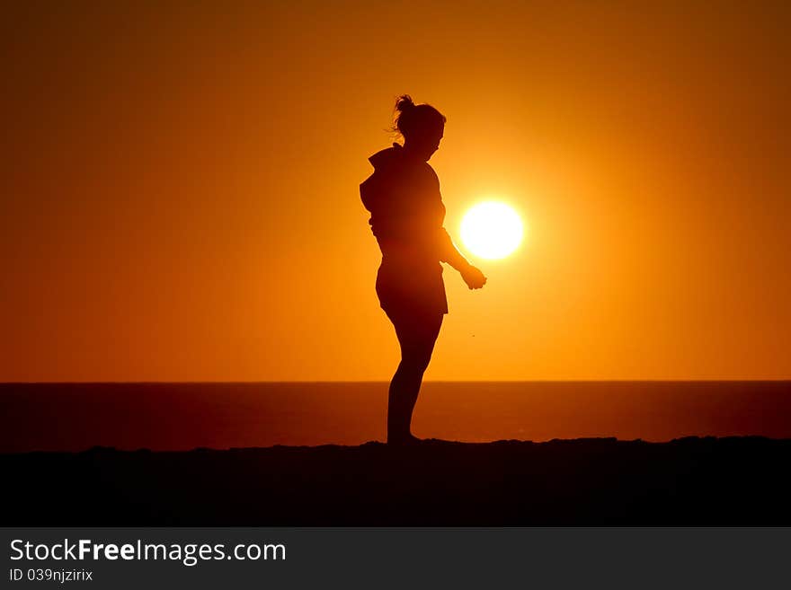 Silhouette of girl standing in sunset at atlantic coast