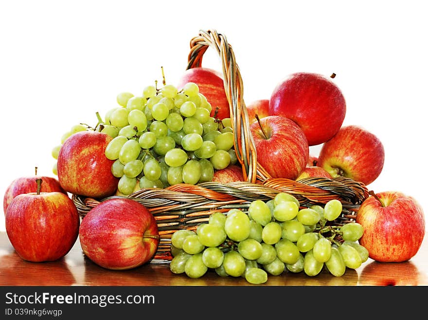 Red apples and grapes in a basket on a white background