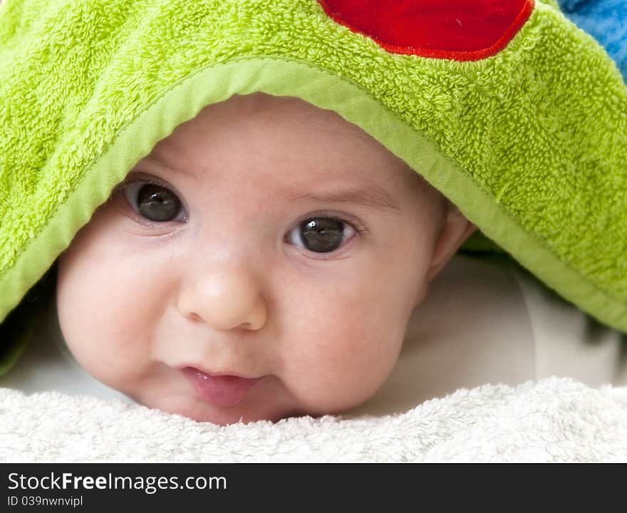 A beautiful smiling baby wrapped in a green blanket. A beautiful smiling baby wrapped in a green blanket