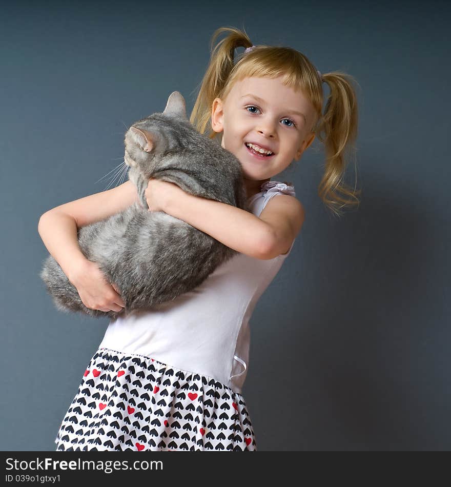 A girl with blond hair is holding a cat and laughs. A girl with blond hair is holding a cat and laughs