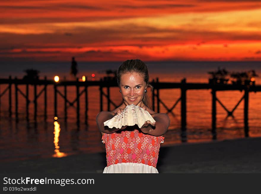 Beautiful young woman holding a seashell during the sunset. Beautiful young woman holding a seashell during the sunset.