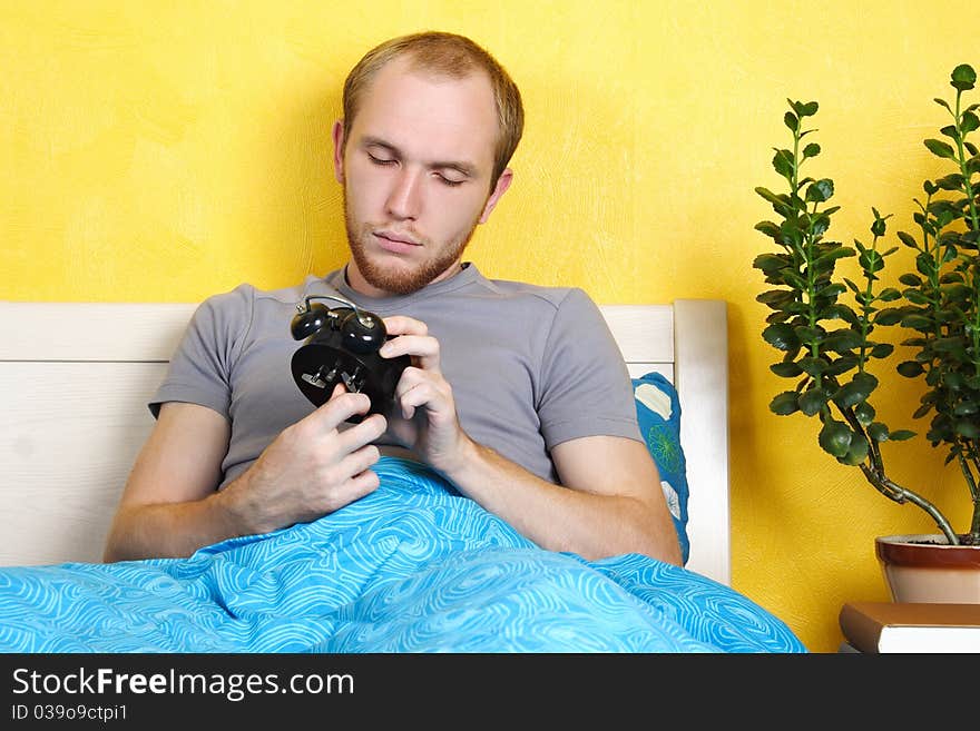 Man lying in bed and winding up alarm clock