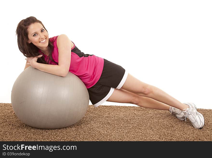 A woman is sideways leaning on a large fitness ball. A woman is sideways leaning on a large fitness ball.