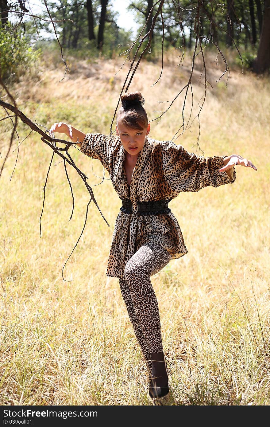 The girl in a suit of a leopard against the wild nature. The girl in a suit of a leopard against the wild nature