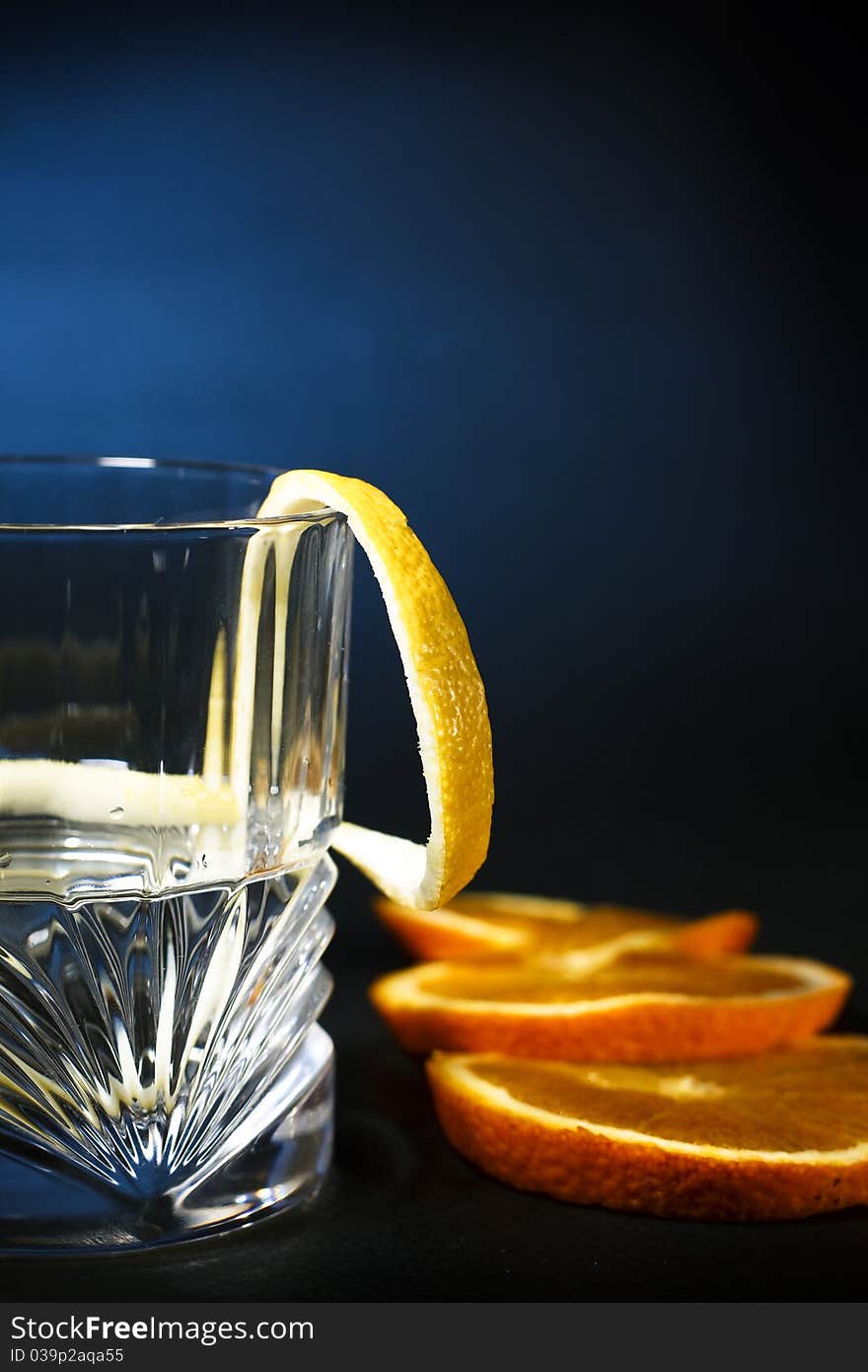 Cold vodka in a glass, with decor oranges and lemon, closeup. Cold vodka in a glass, with decor oranges and lemon, closeup