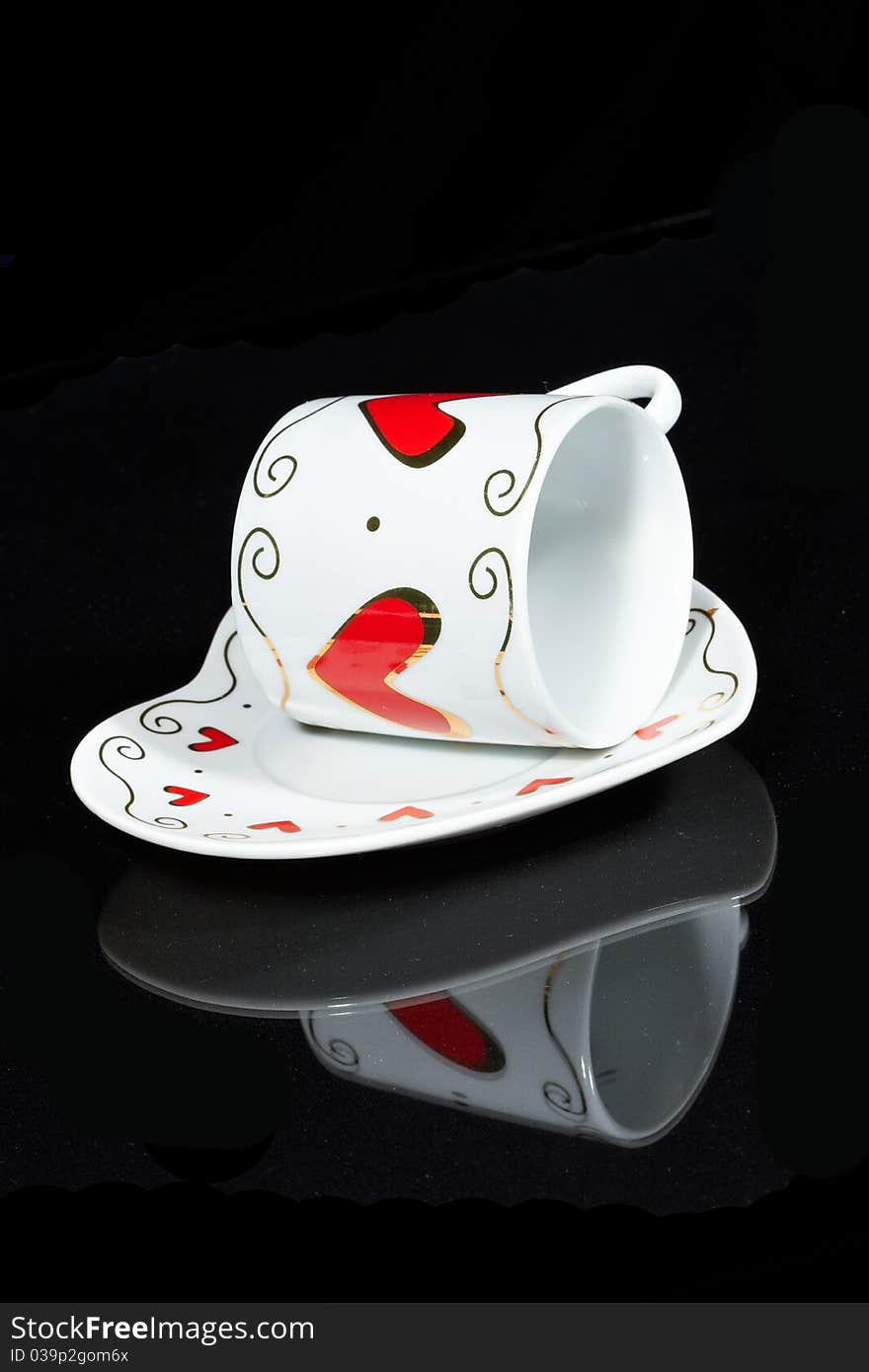 White cup with hearts is a black table, reflected in it. White cup with hearts is a black table, reflected in it.