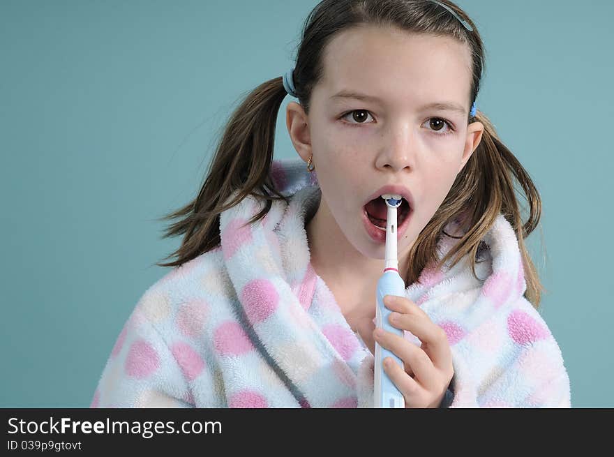 White girl dressed in bathrobe studying electric toothbrush movements. White girl dressed in bathrobe studying electric toothbrush movements