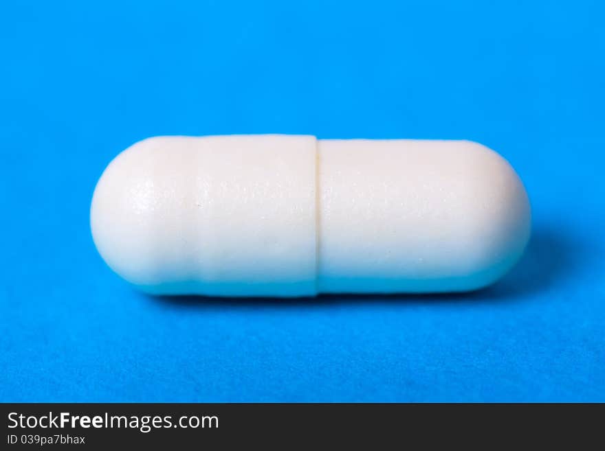 Macro view of white pill on a blue background