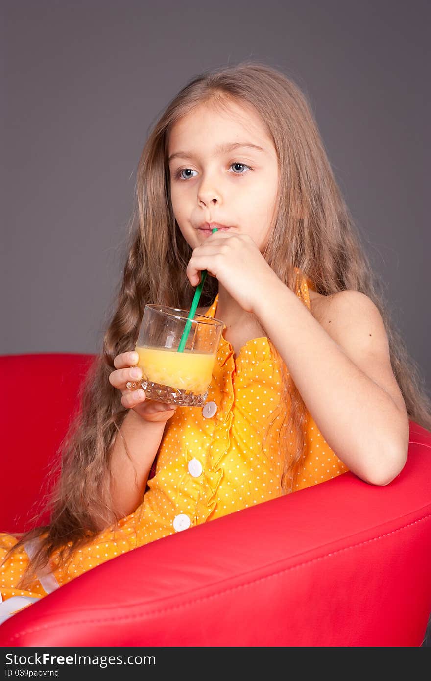 Beautiful young girl drinking orange juice in the studio