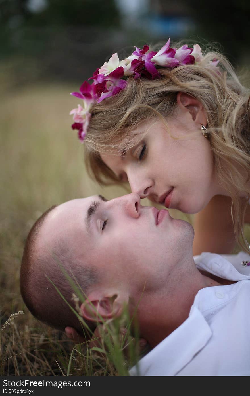 The girl kisses softly the guy lying on a grass. The girl kisses softly the guy lying on a grass