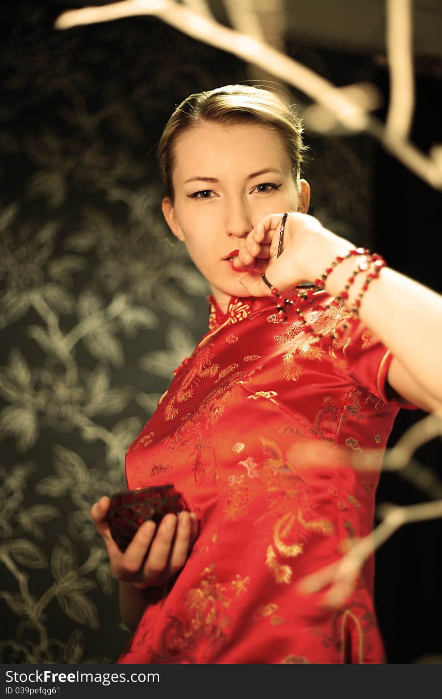 The girl in a red kimono looks at a beads. (Small depth of sharpness). The girl in a red kimono looks at a beads. (Small depth of sharpness)